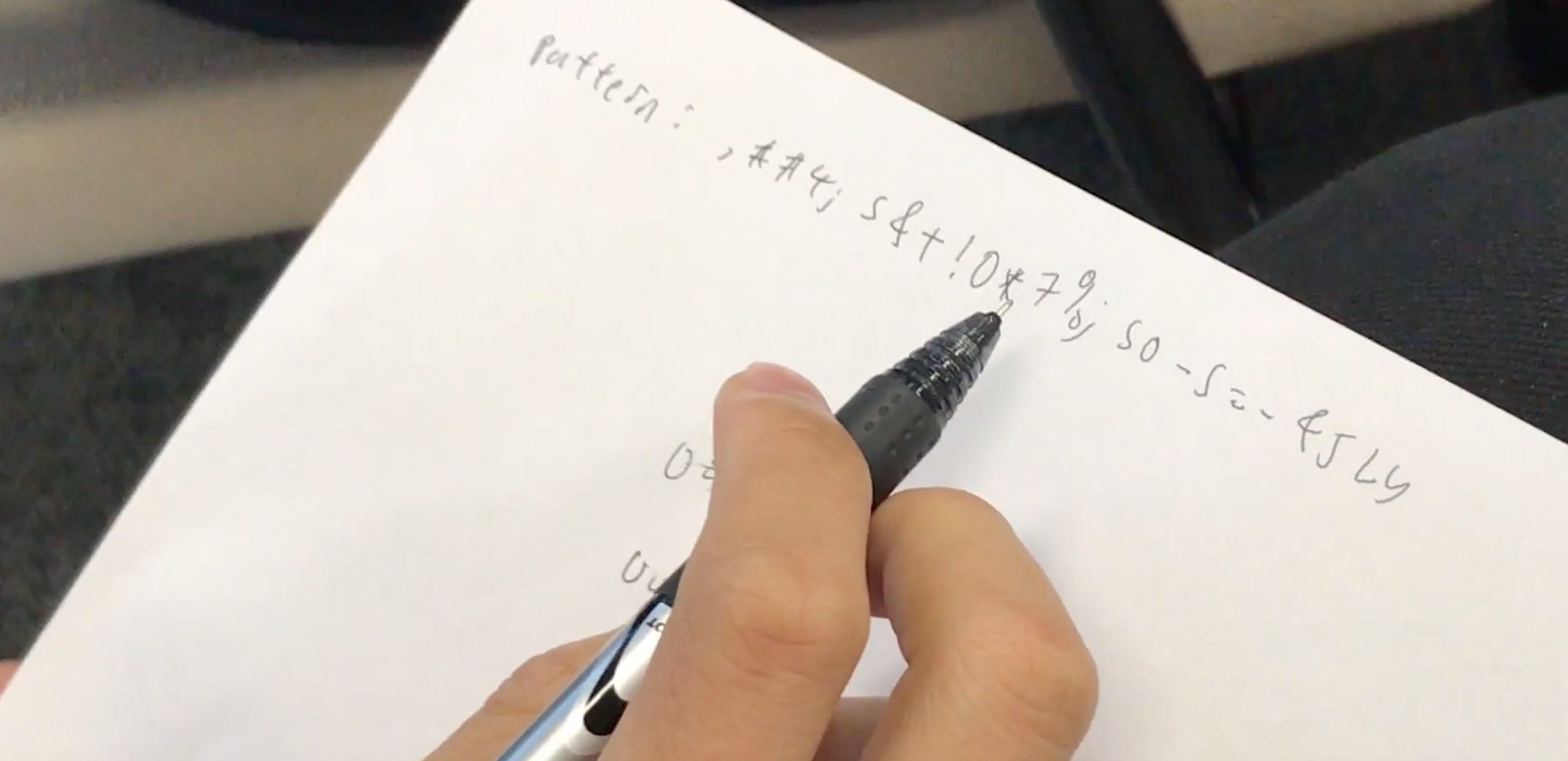 A hand writes notes while working through the cryptography challenge