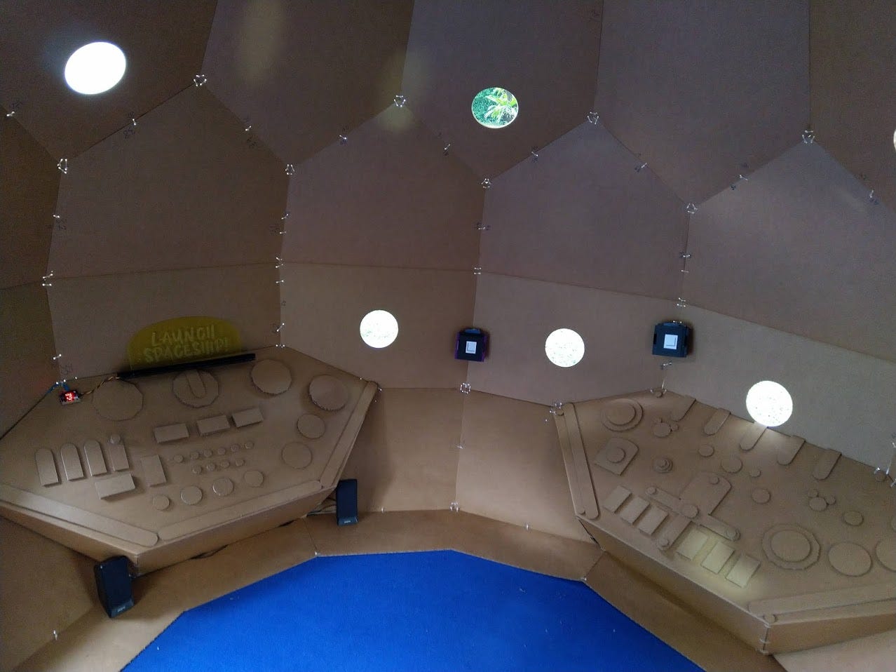 Cardboard spaceship control room with panels and a “Launch Spaceship” sign