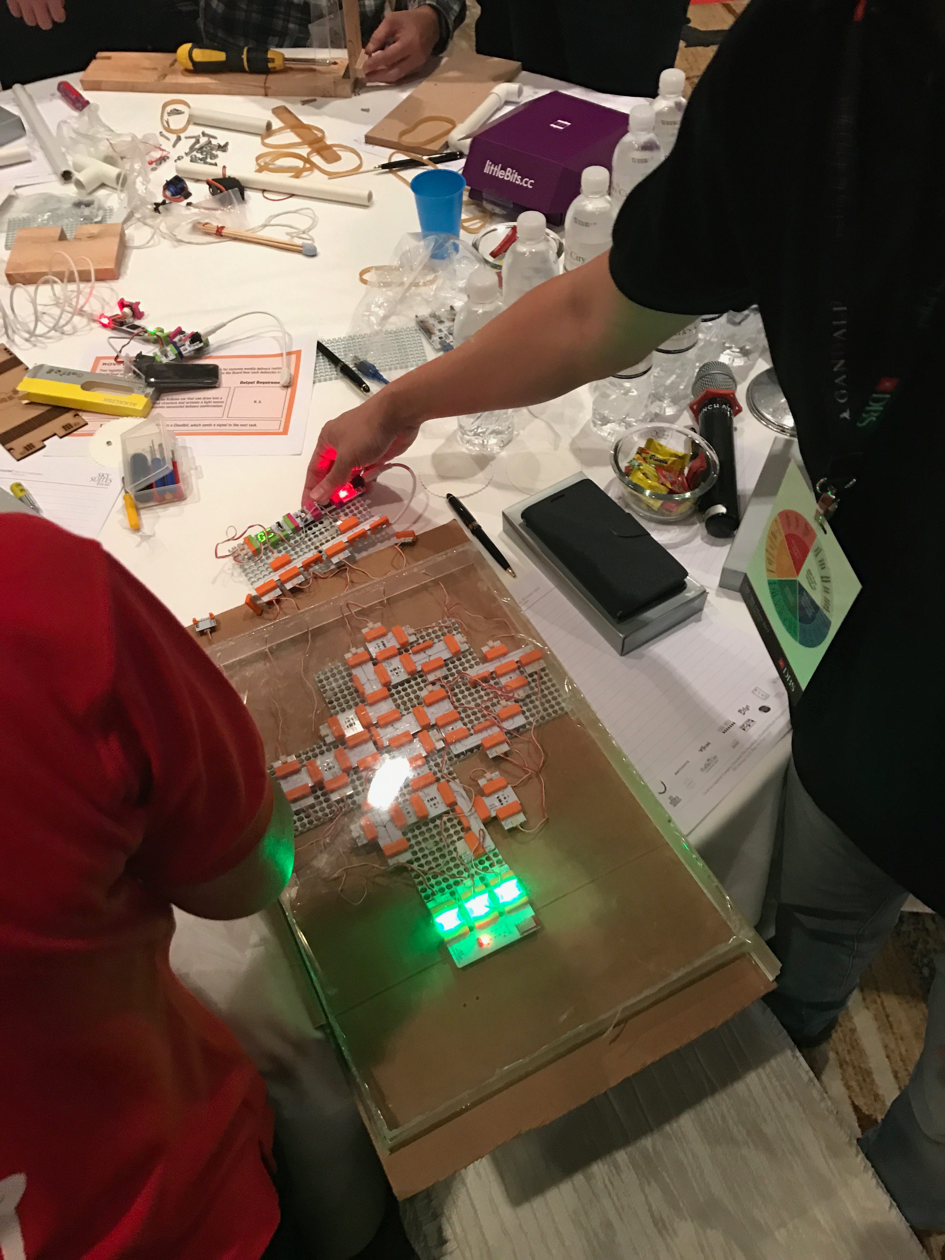 Participants assembling littleBits CloudBit circuits among wires and tools