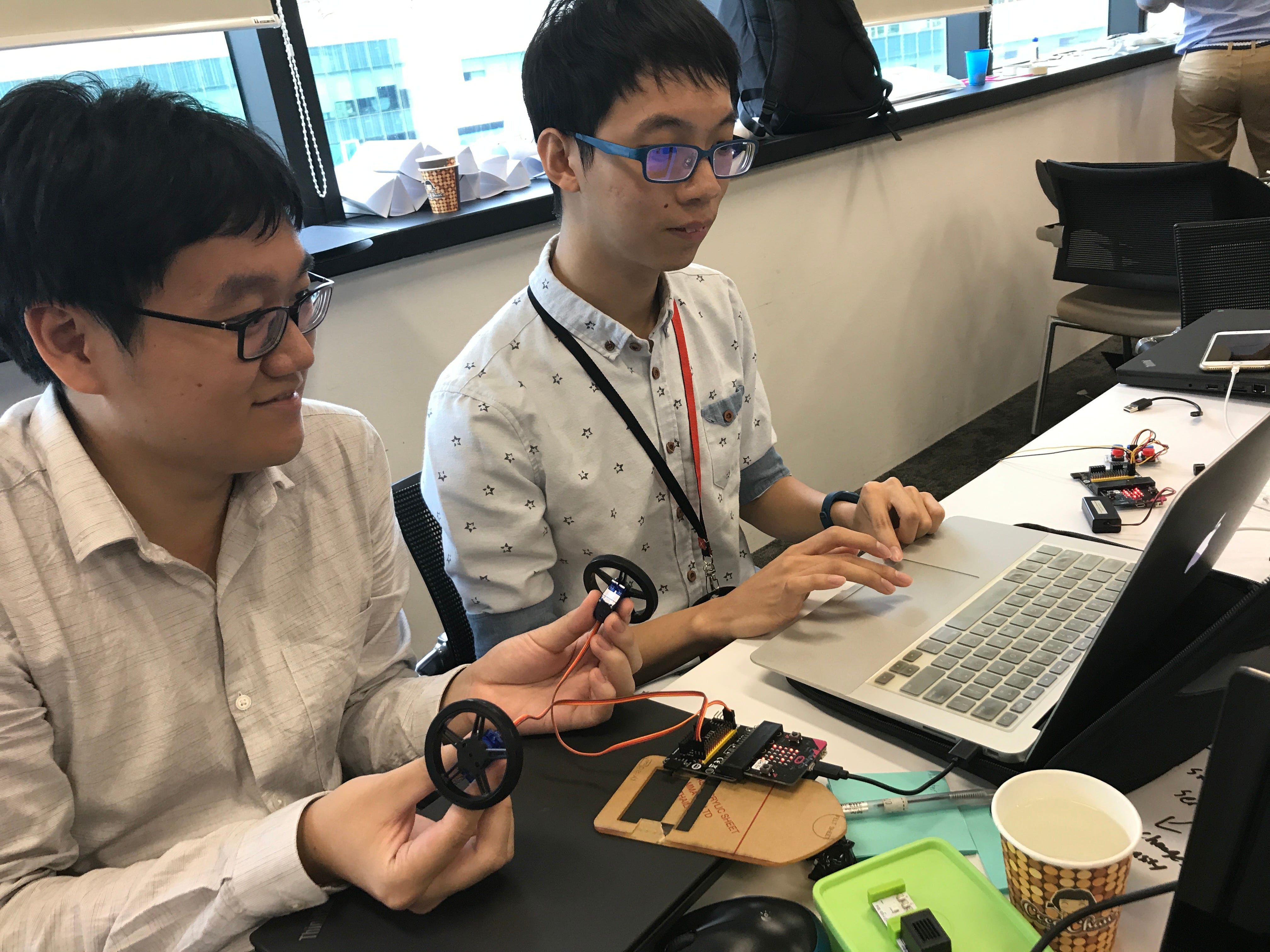 Participants testing wired wheel assemblies beside a micro:bit and laptop