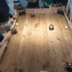 Remote-controlled robots converge on a ball and reposition during a tabletop football match