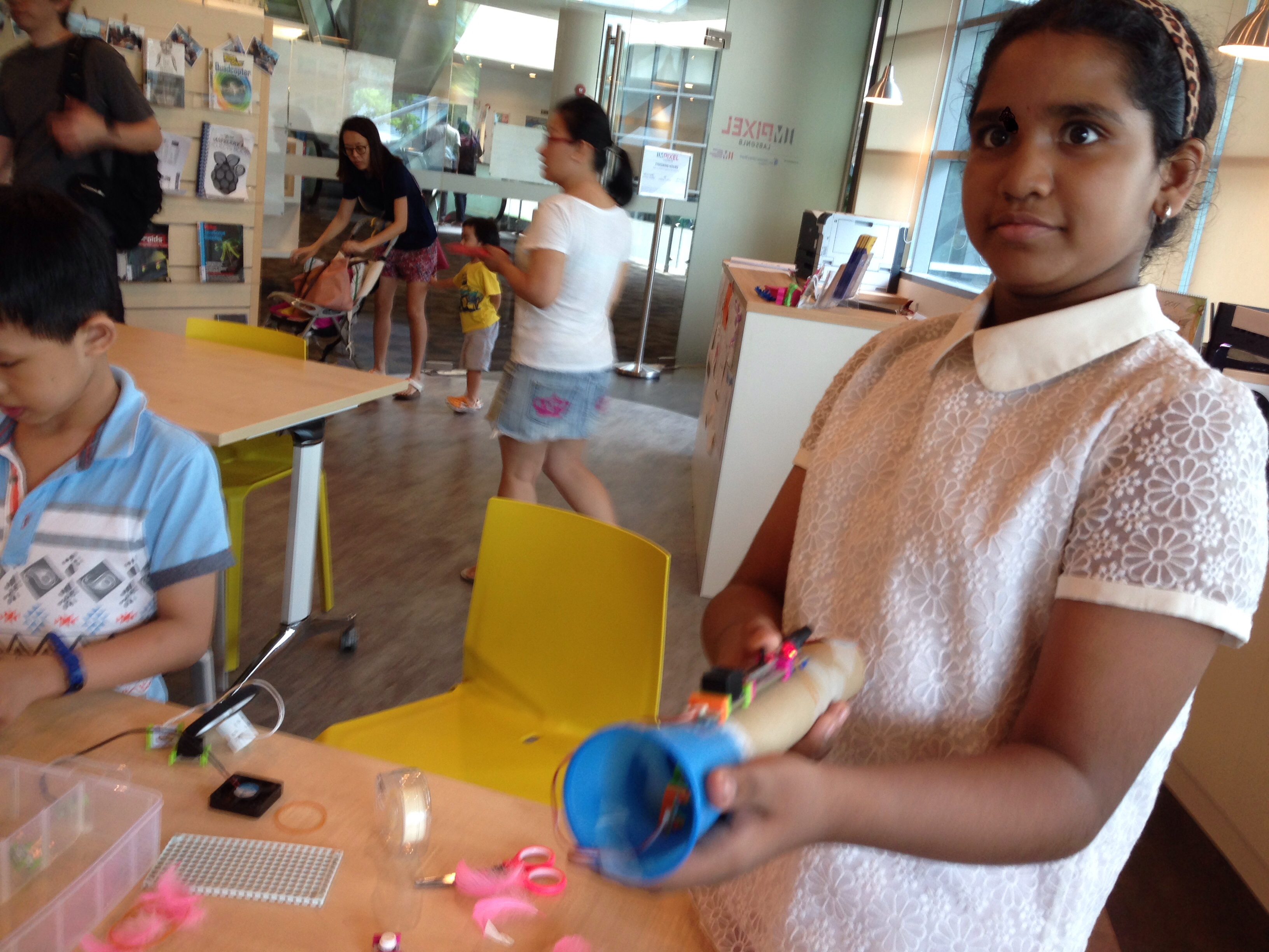 A child holds a cardboard-tube creation fitted with colourful littleBits components during a workshop.