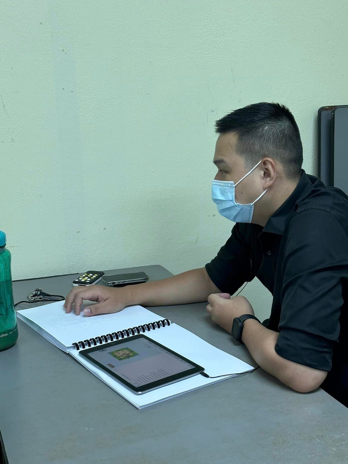 Participant examining a spiral-bound tactile map beside a tablet