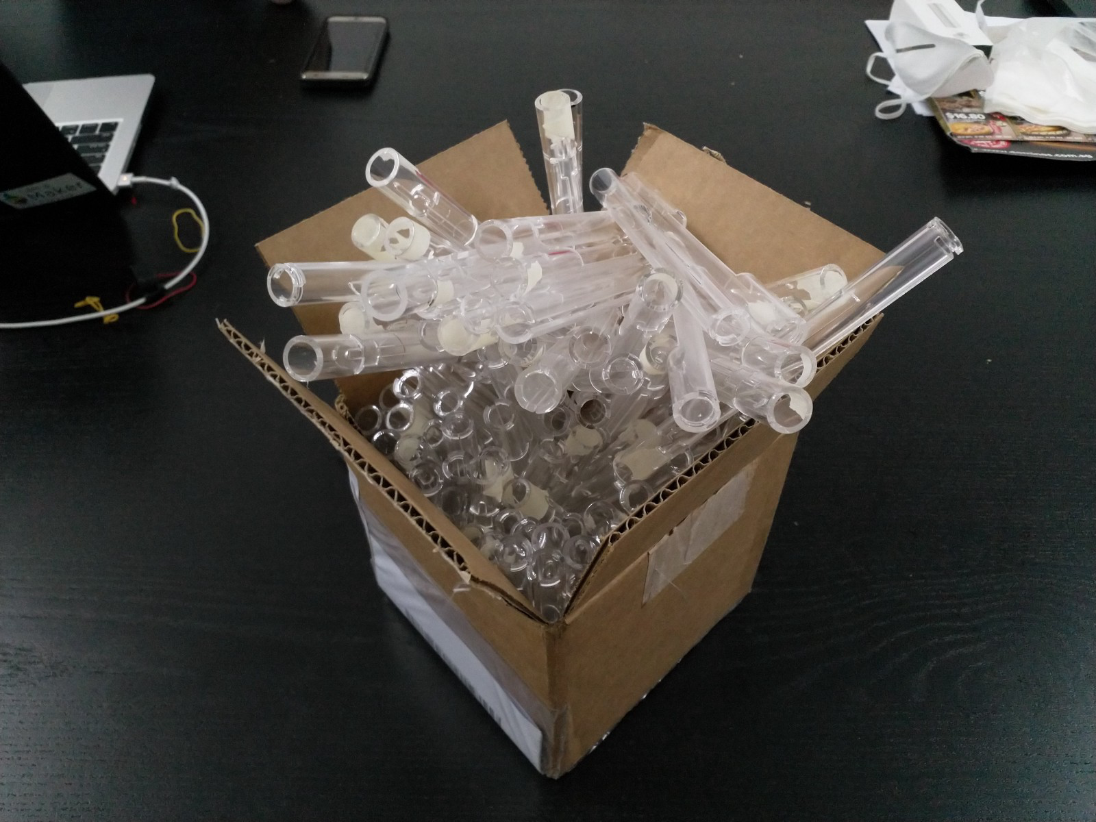 Cardboard box filled with clear acrylic tubes and white end pieces