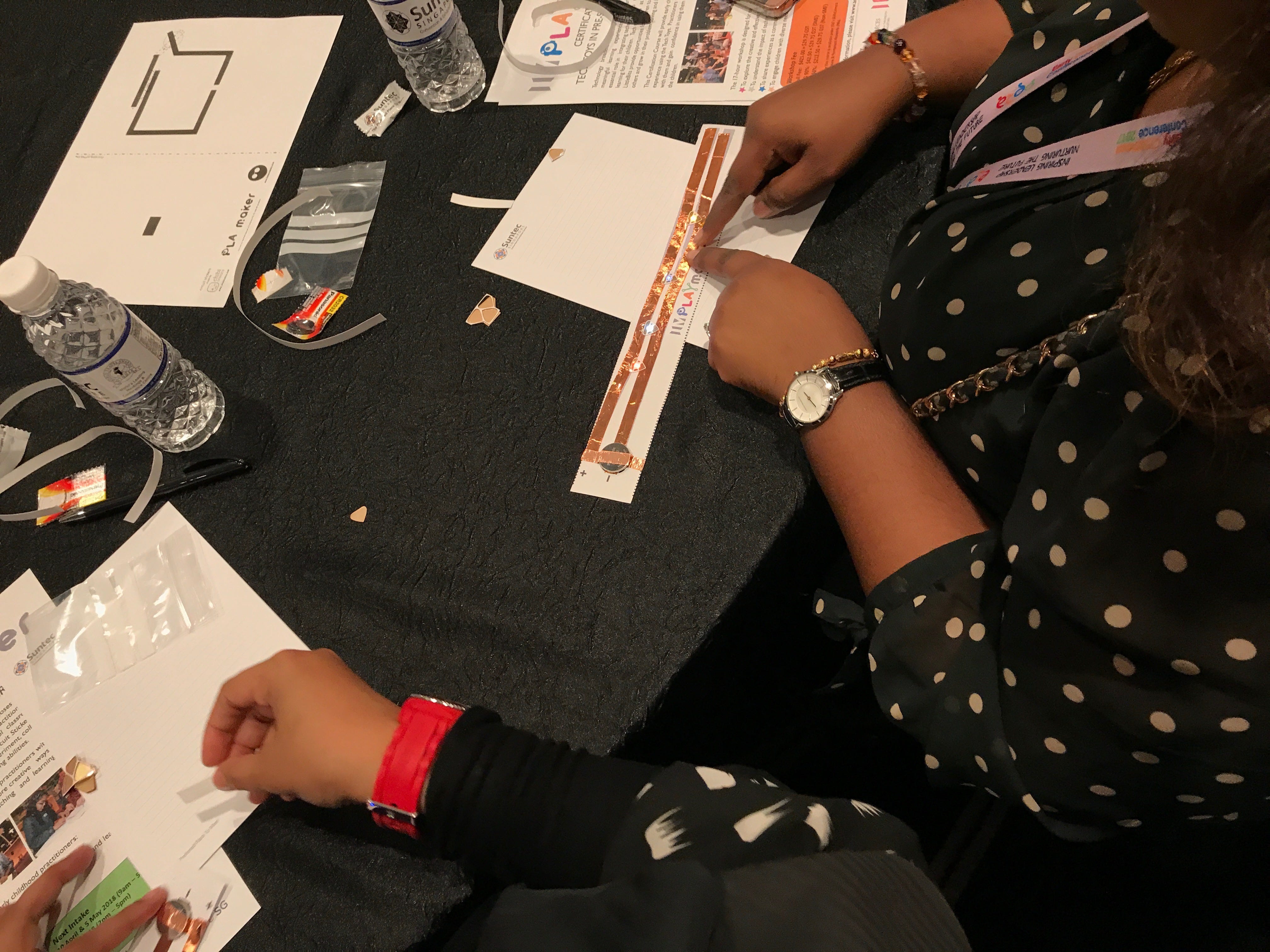 Workshop participants attach copper tape and LEDs to circuit-sticker activity sheets.