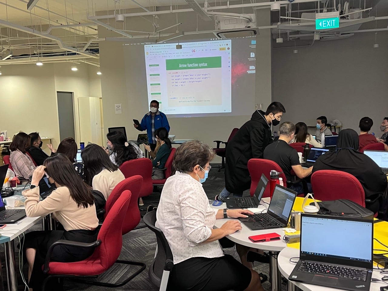 Akmal (front left) teaching participants JavaScript and providing examples for them to follow.