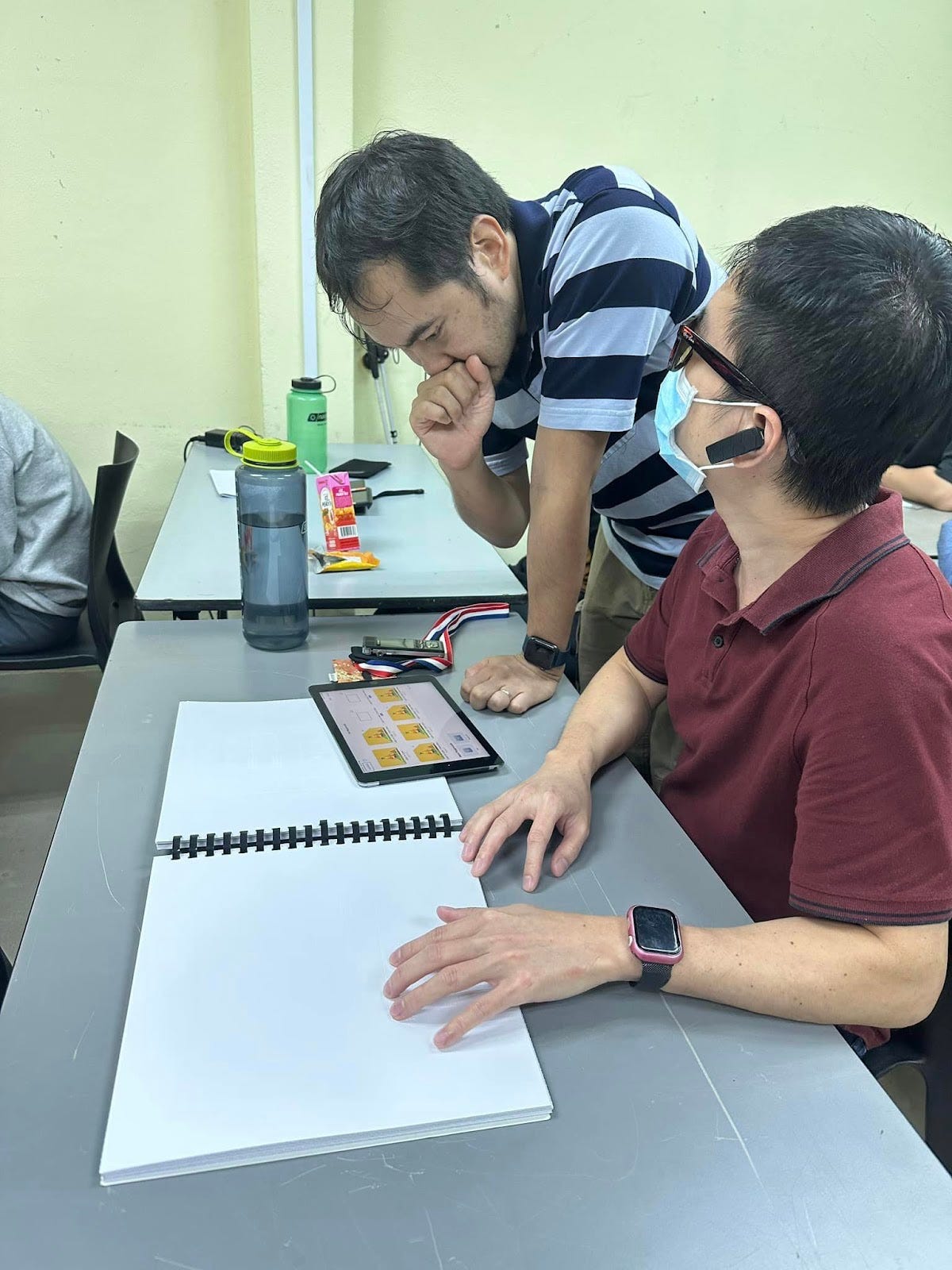 Participants using tactile maps with embossed tactile graphics to orientate themselves around each 3D world.